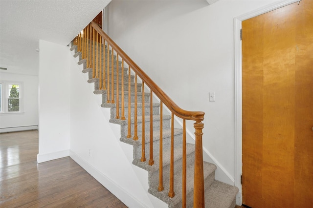 stairs featuring wood finished floors, baseboards, and baseboard heating