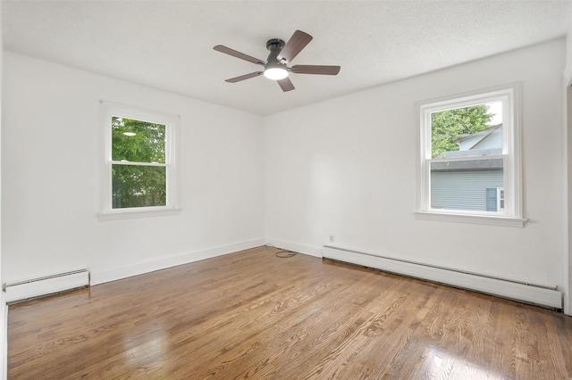 spare room with baseboard heating, a baseboard radiator, wood finished floors, a ceiling fan, and baseboards