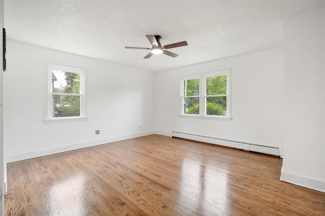 spare room with baseboard heating, ceiling fan, wood finished floors, a textured ceiling, and baseboards