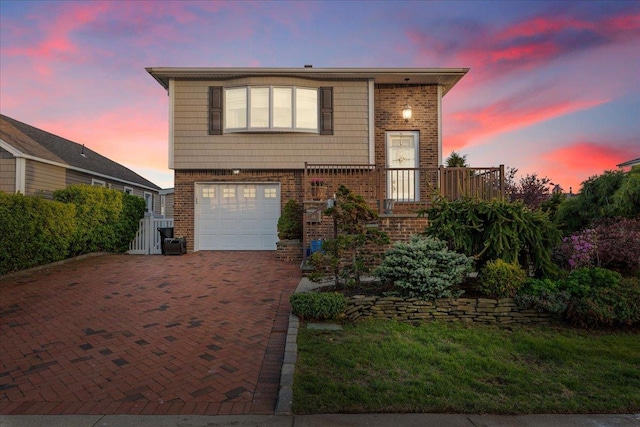 view of front facade featuring an attached garage, brick siding, decorative driveway, and central air condition unit