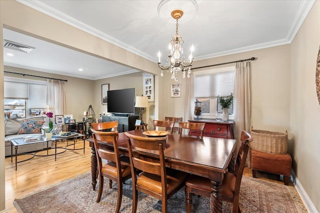 dining room featuring plenty of natural light, wood finished floors, a chandelier, and ornamental molding