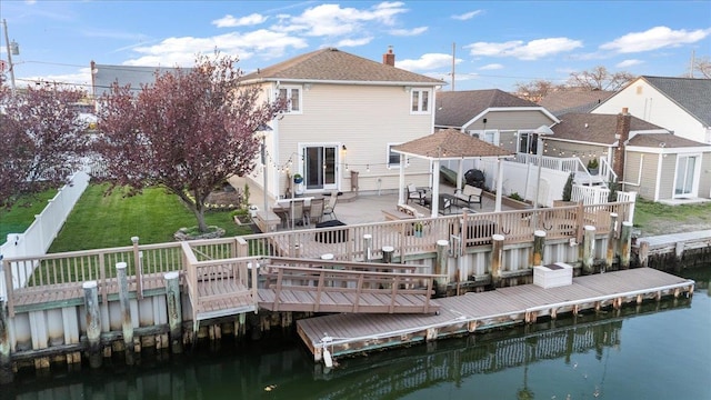 rear view of house featuring a patio area, a deck with water view, a chimney, and outdoor dining area