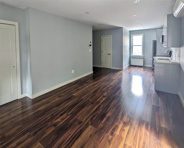 58-09 61st St, Maspeth, NY 11379 - unfurnished living room featuring radiator heating unit, a wall unit AC, dark wood-style flooring, and recessed lighting