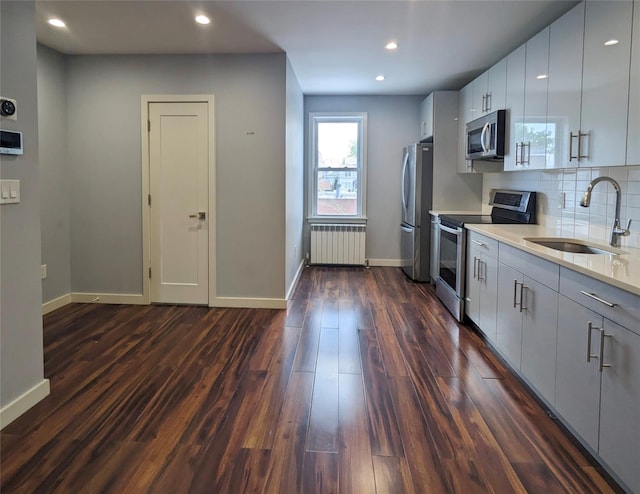 58-09 61st St, Maspeth, NY 11379 - kitchen featuring appliances with stainless steel finishes, radiator heating unit, dark wood-style floors, light countertops, and decorative backsplash