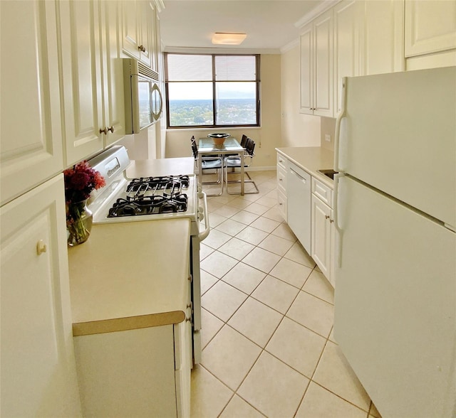 kitchen with white appliances, light tile patterned flooring, light countertops, white cabinets, and crown molding