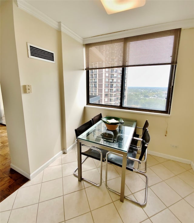 tiled dining room with ornamental molding, plenty of natural light, and baseboards