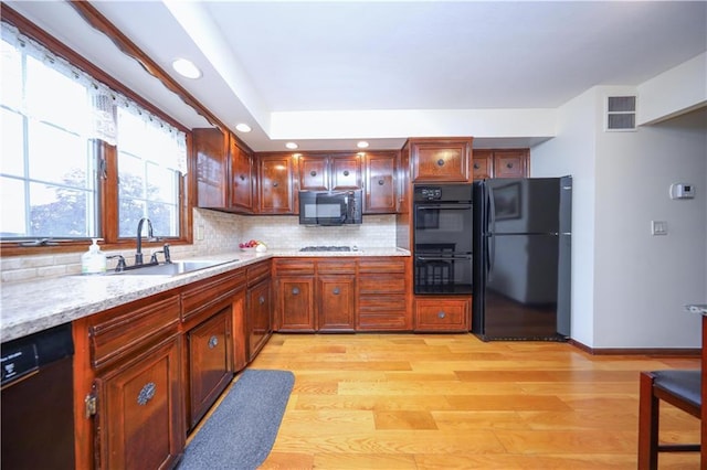 kitchen featuring black appliances, a sink, light wood-type flooring, tasteful backsplash, and recessed lighting