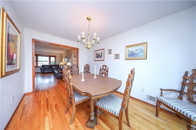 dining area featuring a chandelier, light wood-style floors, and baseboards