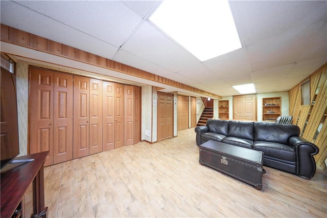 living room featuring stairway, wood finished floors, and a drop ceiling