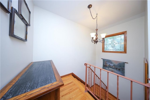 corridor with an upstairs landing, a chandelier, wood finished floors, and baseboards