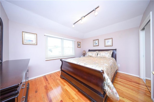 bedroom featuring track lighting, baseboards, and light wood finished floors