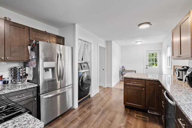 108 Homestead Ave, Maybrook, NY 12543 - kitchen with stainless steel appliances, washer / dryer, dark wood-style flooring, decorative backsplash, and light stone countertops