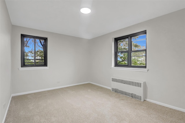 carpeted spare room with radiator and baseboards
