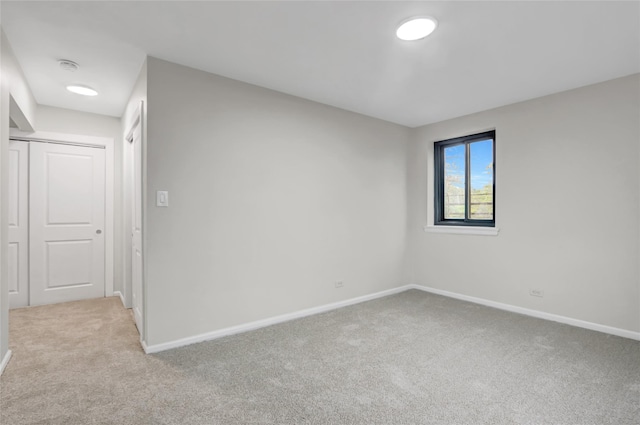 unfurnished room with light colored carpet and baseboards
