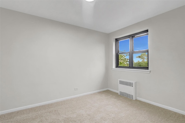 carpeted empty room with radiator and baseboards