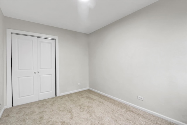 unfurnished bedroom with carpet floors, baseboards, and a closet