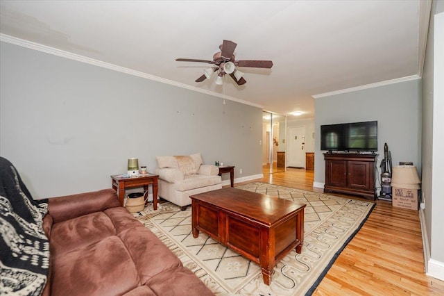 living room featuring a ceiling fan, crown molding, light wood-type flooring, and baseboards