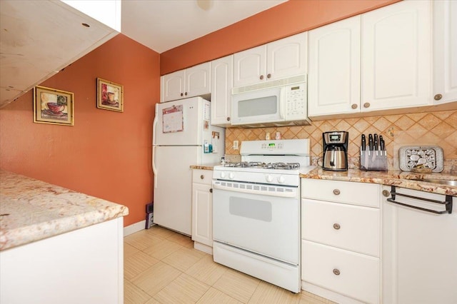 kitchen with white appliances, white cabinetry, tasteful backsplash, light flooring, and light stone counters
