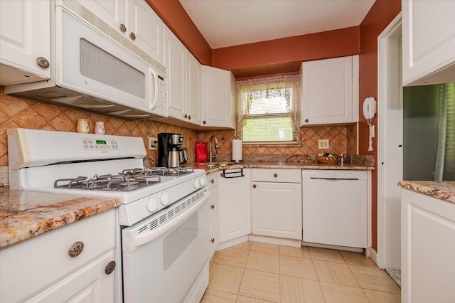 kitchen with white appliances, a sink, white cabinets, backsplash, and light stone countertops