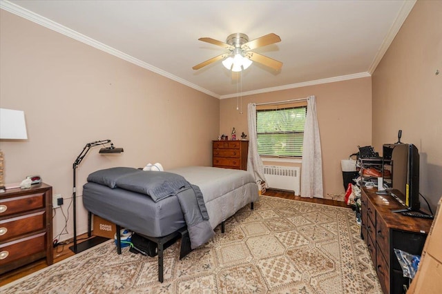 bedroom featuring radiator, ornamental molding, wood finished floors, and a ceiling fan