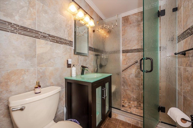 bathroom featuring tile walls, a shower stall, toilet, vanity, and ornamental molding