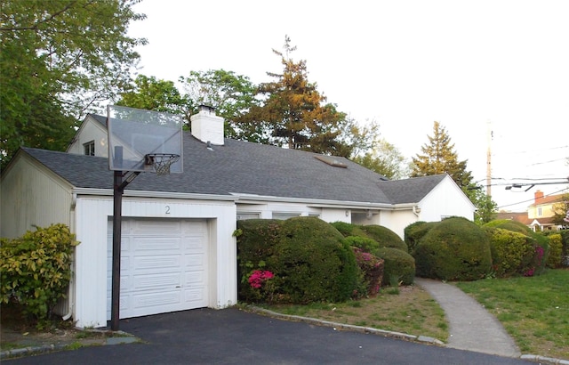 view of side of home with a chimney, roof with shingles, and a garage