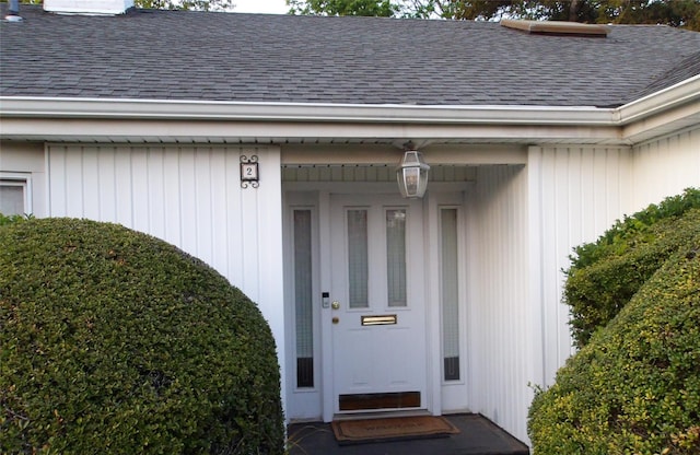 property entrance with a shingled roof and a chimney