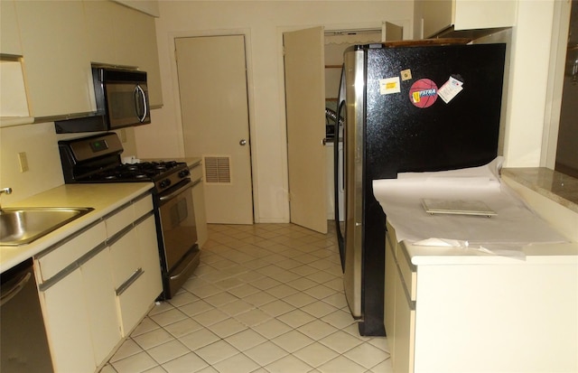 kitchen featuring stainless steel appliances, a sink, light countertops, white cabinets, and light tile patterned floors