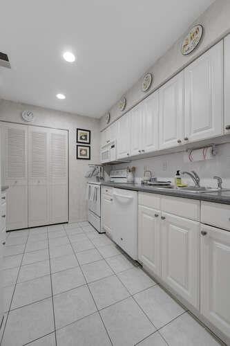 141 Southgate Dr, Massapequa Park, NY 11762 - kitchen with white appliances, white cabinetry, light tile patterned flooring, recessed lighting, and a sink