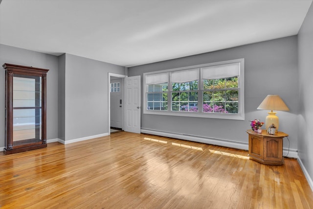 living area featuring a baseboard radiator, a baseboard heating unit, light wood-type flooring, and baseboards