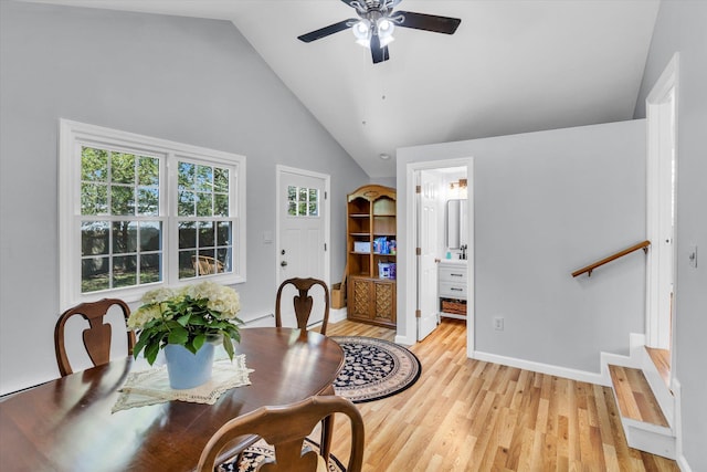 dining room with a ceiling fan, light wood-type flooring, vaulted ceiling, and baseboards