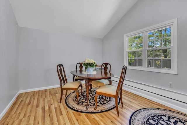 dining area with a baseboard heating unit, lofted ceiling, light wood-style floors, and baseboards
