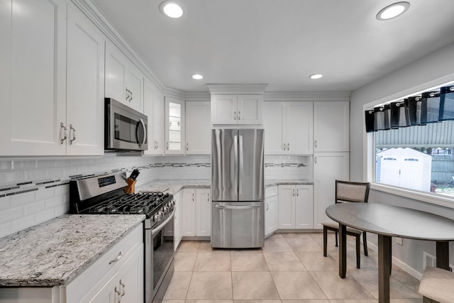 187 Mark Tree Rd, Centereach, NY 11720 - kitchen featuring appliances with stainless steel finishes, white cabinetry, tasteful backsplash, light tile patterned flooring, and recessed lighting