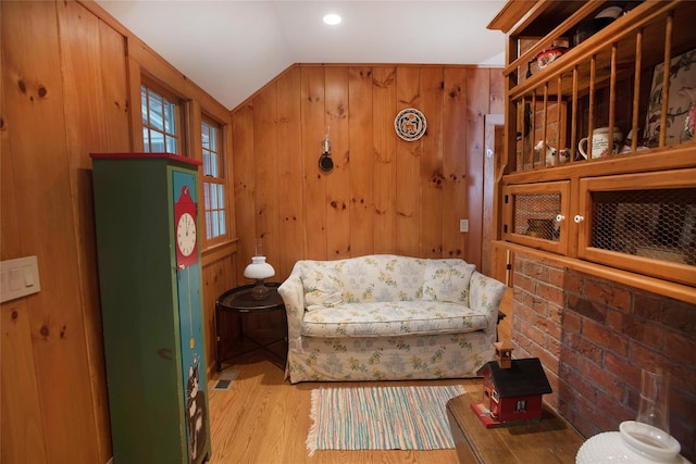 living area featuring vaulted ceiling, wood finished floors, and wood walls