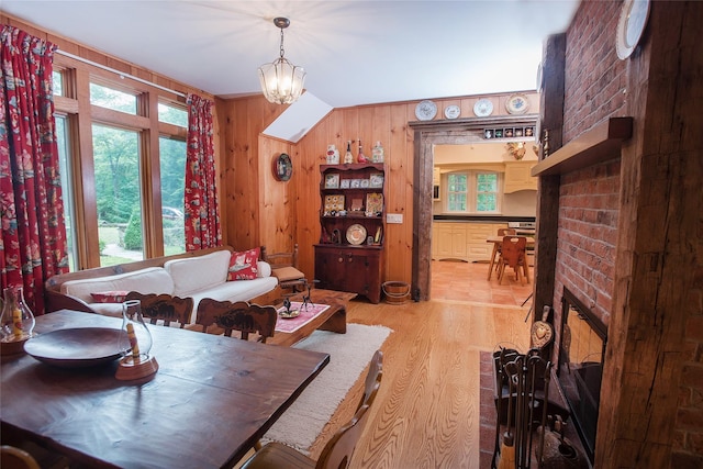 dining area featuring wood walls, light wood-style floors, and a chandelier