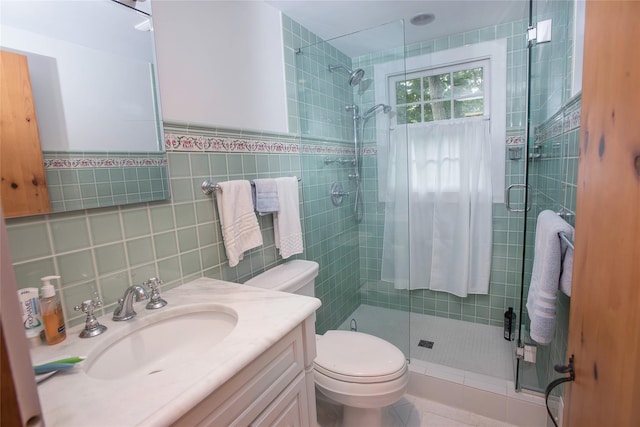 bathroom featuring tile walls, toilet, a stall shower, vanity, and tile patterned floors