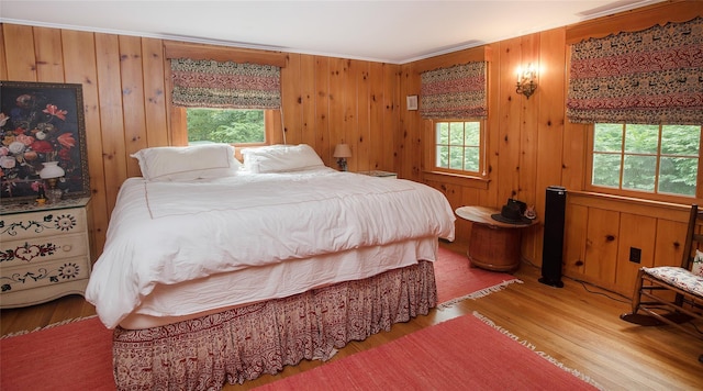 bedroom featuring wood finished floors, ornamental molding, and wood walls