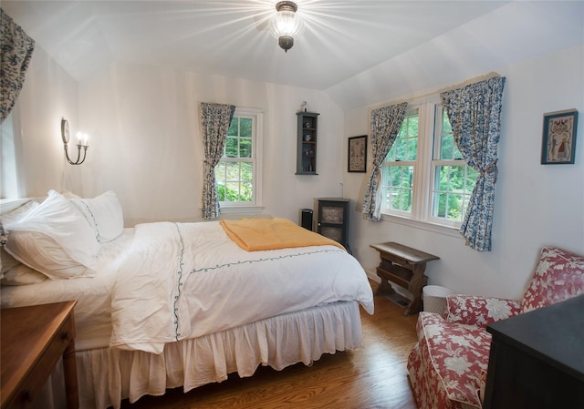 bedroom with multiple windows, wood finished floors, and vaulted ceiling