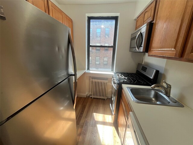 215-44 47th Ave Unit 2B, Bayside, NY 11361 - kitchen with stainless steel appliances, radiator, a sink, and brown cabinets