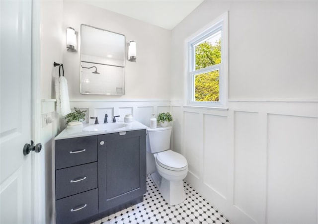 bathroom with toilet, a wainscoted wall, vanity, a decorative wall, and tile patterned floors