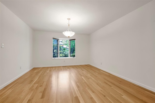 unfurnished room featuring baseboards and light wood finished floors