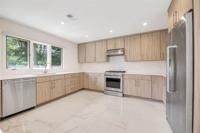 kitchen with appliances with stainless steel finishes, light brown cabinets, light marble finish flooring, under cabinet range hood, and recessed lighting