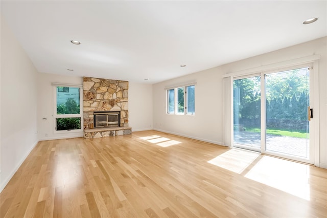 unfurnished living room with light wood finished floors, baseboards, a fireplace, and recessed lighting