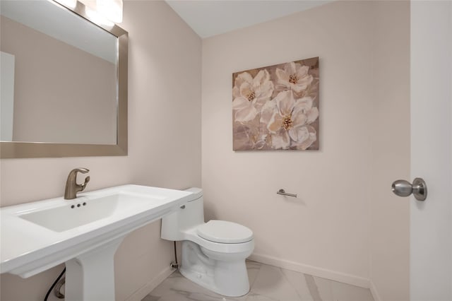 bathroom with marble look tiles, toilet, and baseboards