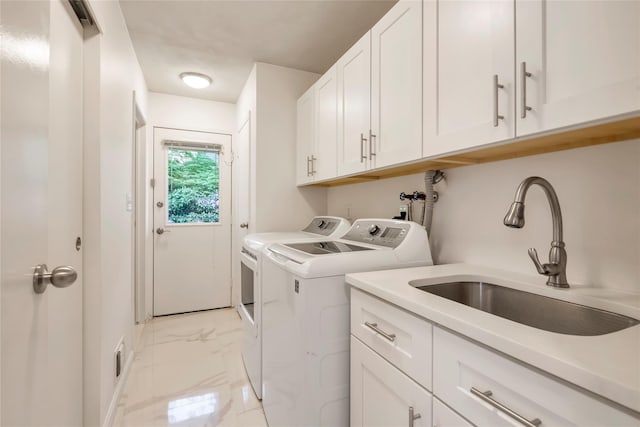 laundry area featuring light marble finish floors, washer and clothes dryer, and cabinet space