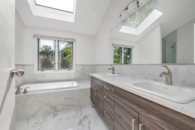 full bathroom with a skylight, marble look tiles, vaulted ceiling, a stall shower, and a bath