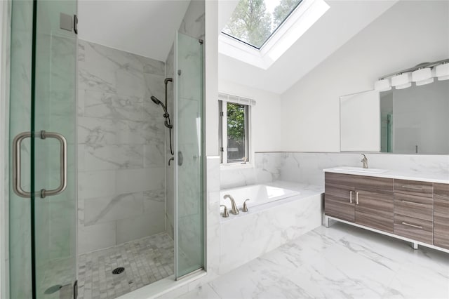 bathroom with vaulted ceiling, a skylight, marble finish flooring, a stall shower, and vanity