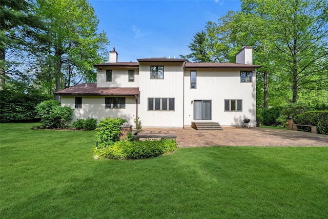 back of house featuring a chimney, a yard, and a patio