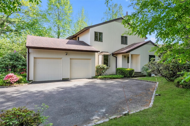 view of front of property with asphalt driveway, an attached garage, and a front lawn