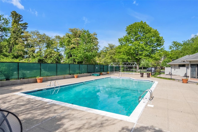 community pool with fence and view of wooded area